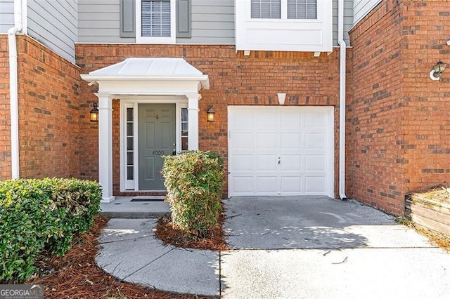 entrance to property with driveway, brick siding, and an attached garage