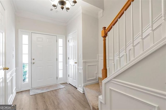 entrance foyer featuring stairway, crown molding, a decorative wall, and visible vents