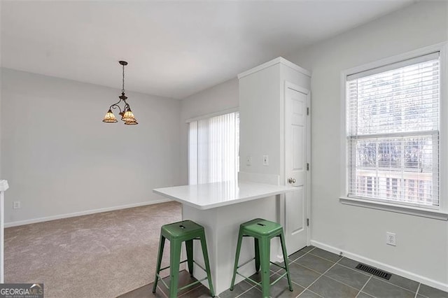 kitchen with visible vents, baseboards, decorative light fixtures, a peninsula, and a notable chandelier