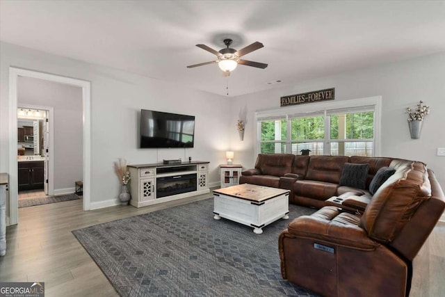 living room with visible vents, baseboards, a ceiling fan, and wood finished floors