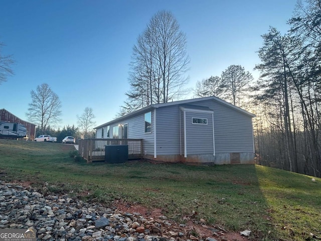 view of side of home with a deck and a yard