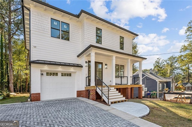 american foursquare style home with covered porch, metal roof, decorative driveway, a garage, and a standing seam roof