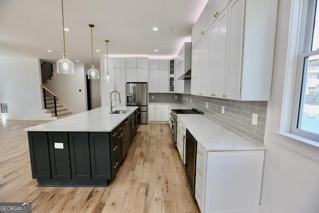 2611 Charlesgate Ave, Decatur, GA 30030 - kitchen with stainless steel appliances, white cabinetry, a sink, light wood-style floors, and tasteful backsplash