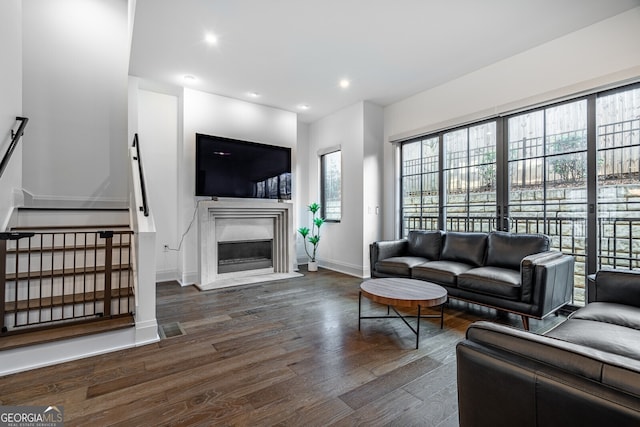 living room featuring visible vents, baseboards, a glass covered fireplace, recessed lighting, and wood finished floors
