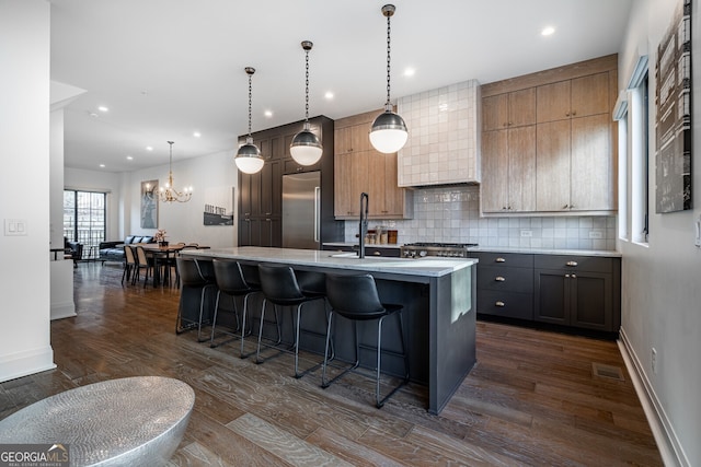 kitchen featuring built in fridge, light countertops, dark wood finished floors, backsplash, and a notable chandelier