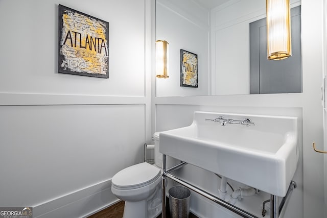 half bath with wood finished floors, a sink, and toilet