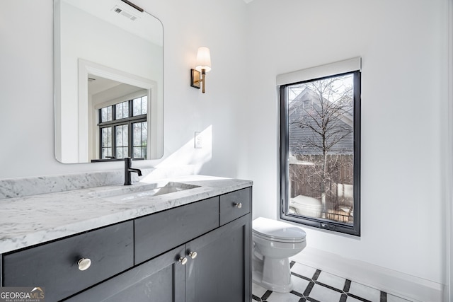 half bath featuring visible vents, a wealth of natural light, vanity, and toilet