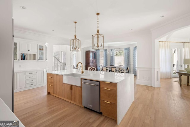 kitchen with a notable chandelier, a sink, stainless steel dishwasher, arched walkways, and light countertops