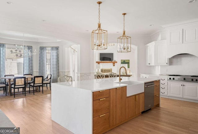 kitchen featuring light countertops, an island with sink, a notable chandelier, white cabinets, and a sink