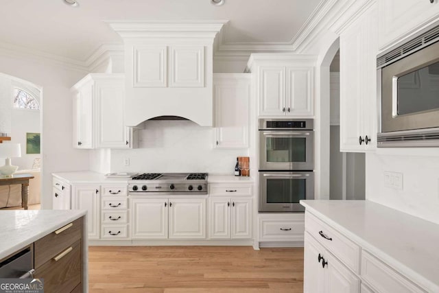 kitchen featuring light wood-type flooring, appliances with stainless steel finishes, white cabinets, crown molding, and light countertops