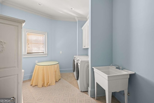 laundry room with baseboards, washing machine and clothes dryer, cabinet space, a sink, and crown molding