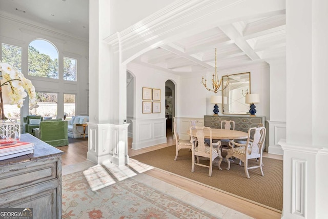 dining area featuring beam ceiling, arched walkways, an inviting chandelier, and crown molding