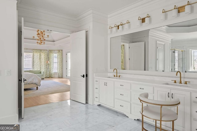 ensuite bathroom with plenty of natural light, marble finish floor, crown molding, and a sink