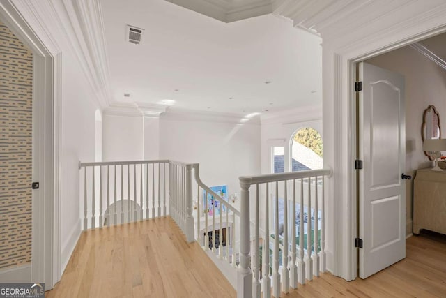 hallway featuring visible vents, an upstairs landing, light wood-style floors, and crown molding