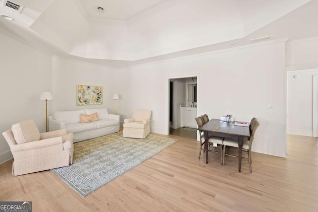 living area with visible vents, ornamental molding, a raised ceiling, and wood finished floors