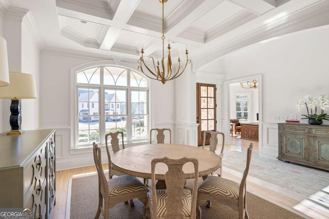 dining room with crown molding, beamed ceiling, light wood-style flooring, an inviting chandelier, and coffered ceiling