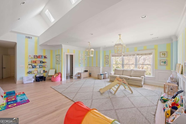 rec room featuring visible vents, a wainscoted wall, ornamental molding, wood finished floors, and a decorative wall