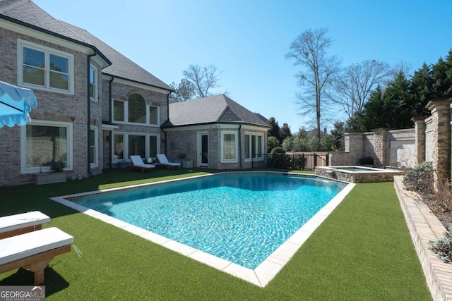 view of pool with a fenced backyard, a pool with connected hot tub, and a yard