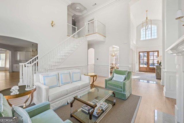 living room featuring a decorative wall, stairs, wood finished floors, arched walkways, and a notable chandelier