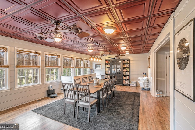 dining room with visible vents, an ornate ceiling, light wood-style floors, and wooden walls