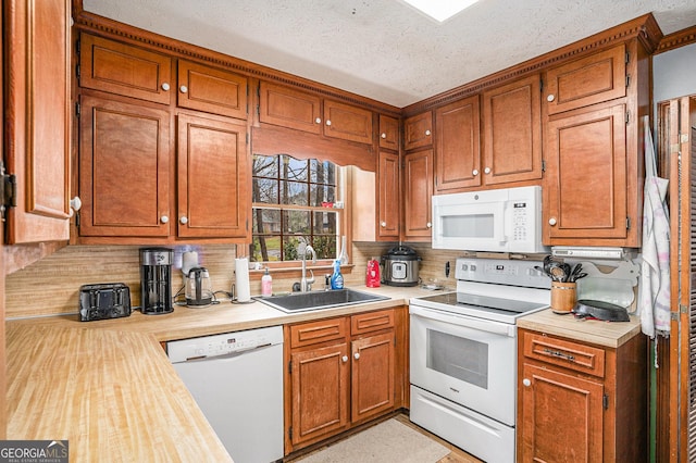 kitchen with tasteful backsplash, light countertops, brown cabinetry, white appliances, and a sink