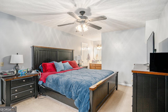 bedroom with a ceiling fan, light colored carpet, ensuite bathroom, and a textured ceiling