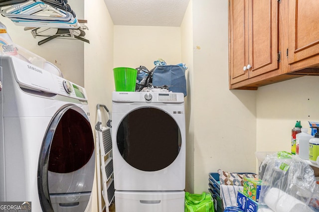 clothes washing area featuring cabinet space, a textured ceiling, and separate washer and dryer