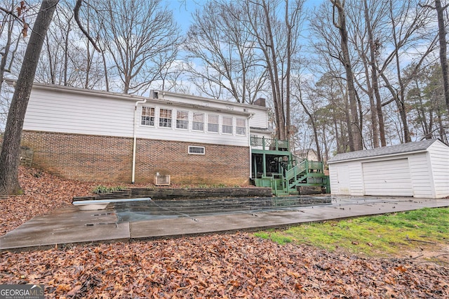 back of property with stairway, a chimney, an outdoor structure, a detached garage, and brick siding