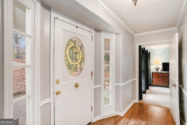 entrance foyer with baseboards, light wood-style floors, ornamental molding, and a textured ceiling