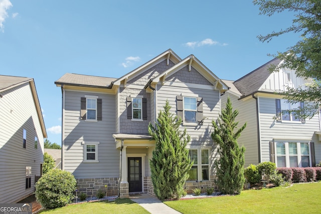 craftsman-style home with stone siding and a front yard