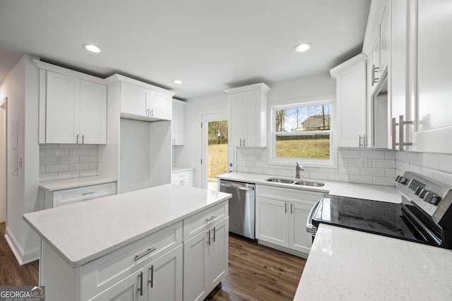 kitchen with a kitchen island, dark wood-style floors, white cabinets, stainless steel appliances, and a sink