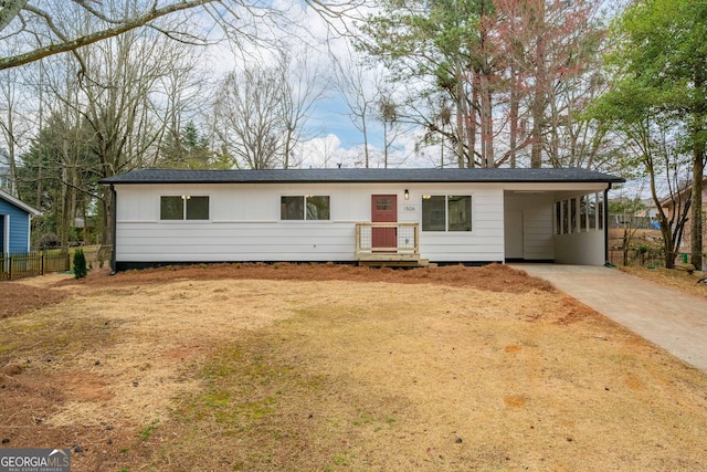 ranch-style home featuring an attached carport, driveway, and fence