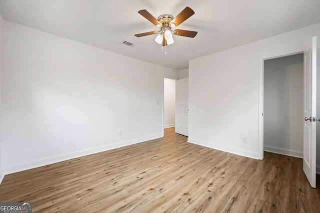 unfurnished bedroom featuring ceiling fan, visible vents, baseboards, and wood finished floors