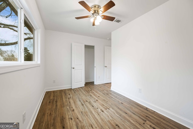 unfurnished bedroom with visible vents, ceiling fan, baseboards, and wood finished floors