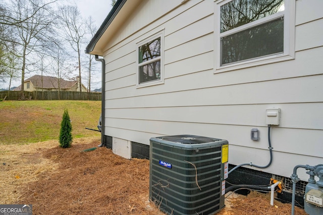 exterior details with gas meter, central air condition unit, and fence