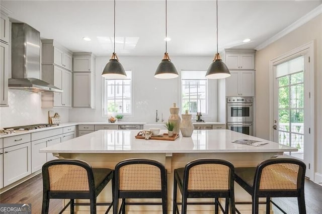 385 Rowes Cir, Alpharetta, GA 30009 - kitchen with wall chimney range hood, appliances with stainless steel finishes, a kitchen island, light countertops, and a breakfast bar area