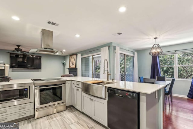 kitchen featuring visible vents, island exhaust hood, a sink, stainless steel appliances, and light countertops