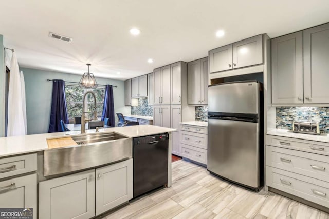 kitchen featuring light countertops, dishwasher, gray cabinets, and freestanding refrigerator