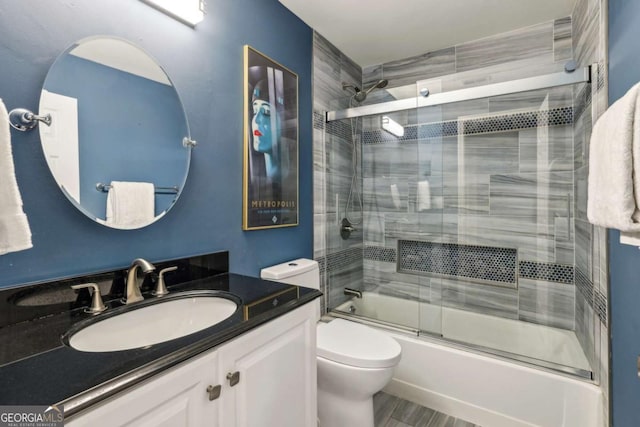 full bathroom featuring shower / bath combination with glass door, toilet, and vanity