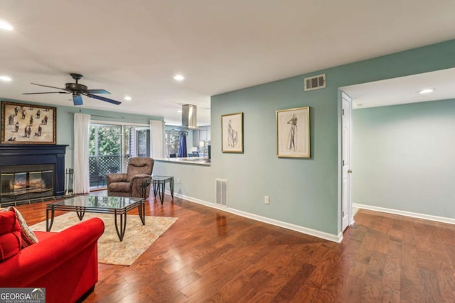 living room with a ceiling fan, wood finished floors, baseboards, and visible vents