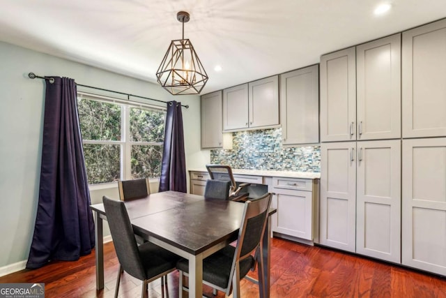 dining area with baseboards, dark wood-style flooring, recessed lighting, and a notable chandelier