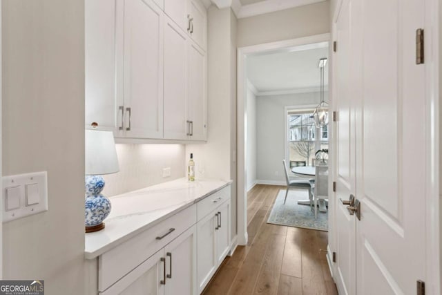 interior space with hardwood / wood-style flooring, crown molding, baseboards, and backsplash