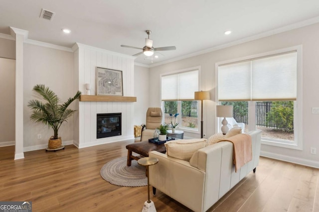 living room featuring ornamental molding, wood finished floors, visible vents, and ceiling fan