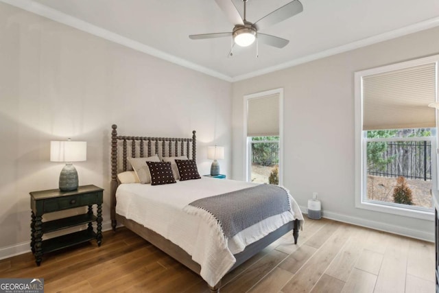 bedroom with a ceiling fan, wood finished floors, baseboards, and ornamental molding