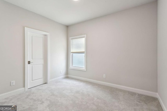 empty room featuring light colored carpet and baseboards