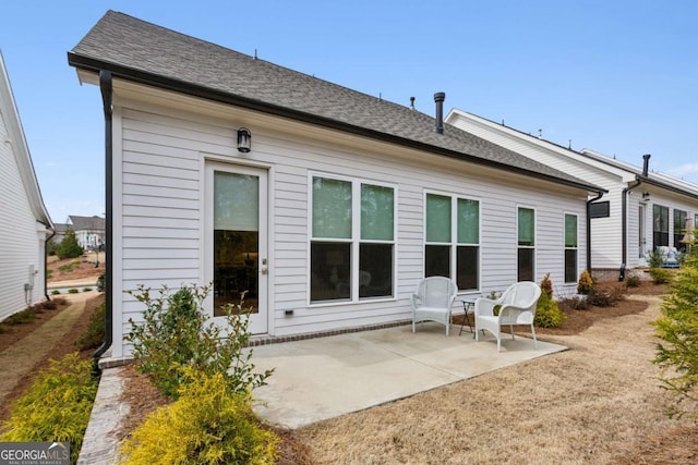 back of property featuring a shingled roof and a patio