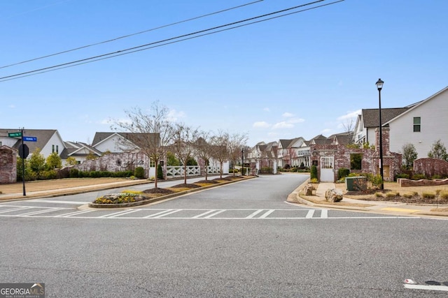 view of road with curbs, a residential view, street lights, and sidewalks