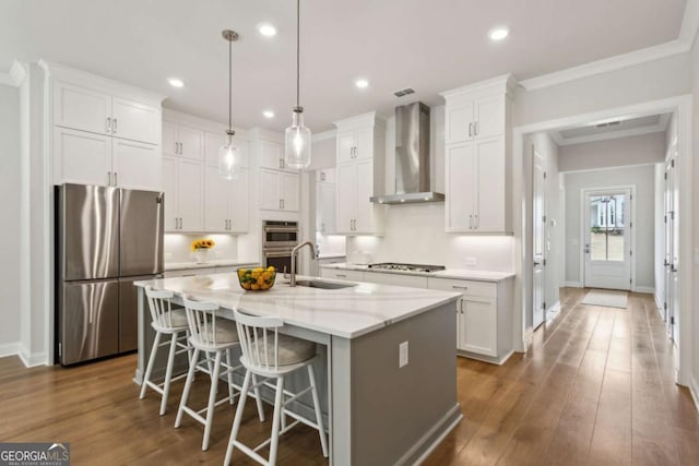 kitchen with a sink, wall chimney range hood, white cabinets, and stainless steel appliances