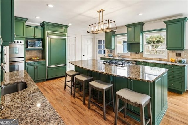 kitchen featuring green cabinetry, appliances with stainless steel finishes, and light wood-style flooring