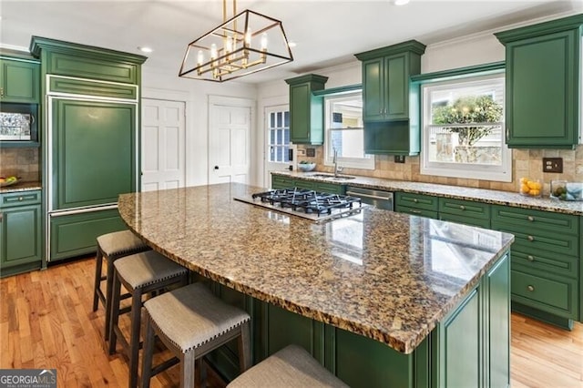 kitchen featuring backsplash, green cabinets, a breakfast bar, light wood-type flooring, and appliances with stainless steel finishes